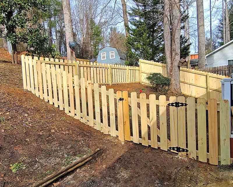 Wooden picket fence with gate on slope